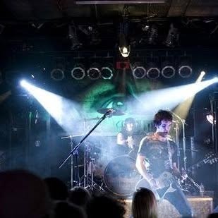 Topher playing guitar under stage lights