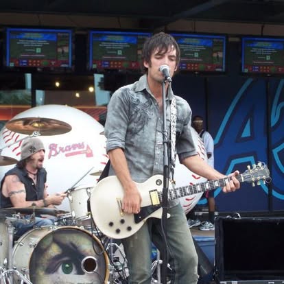 Topher singing and playing guitar with a live band
